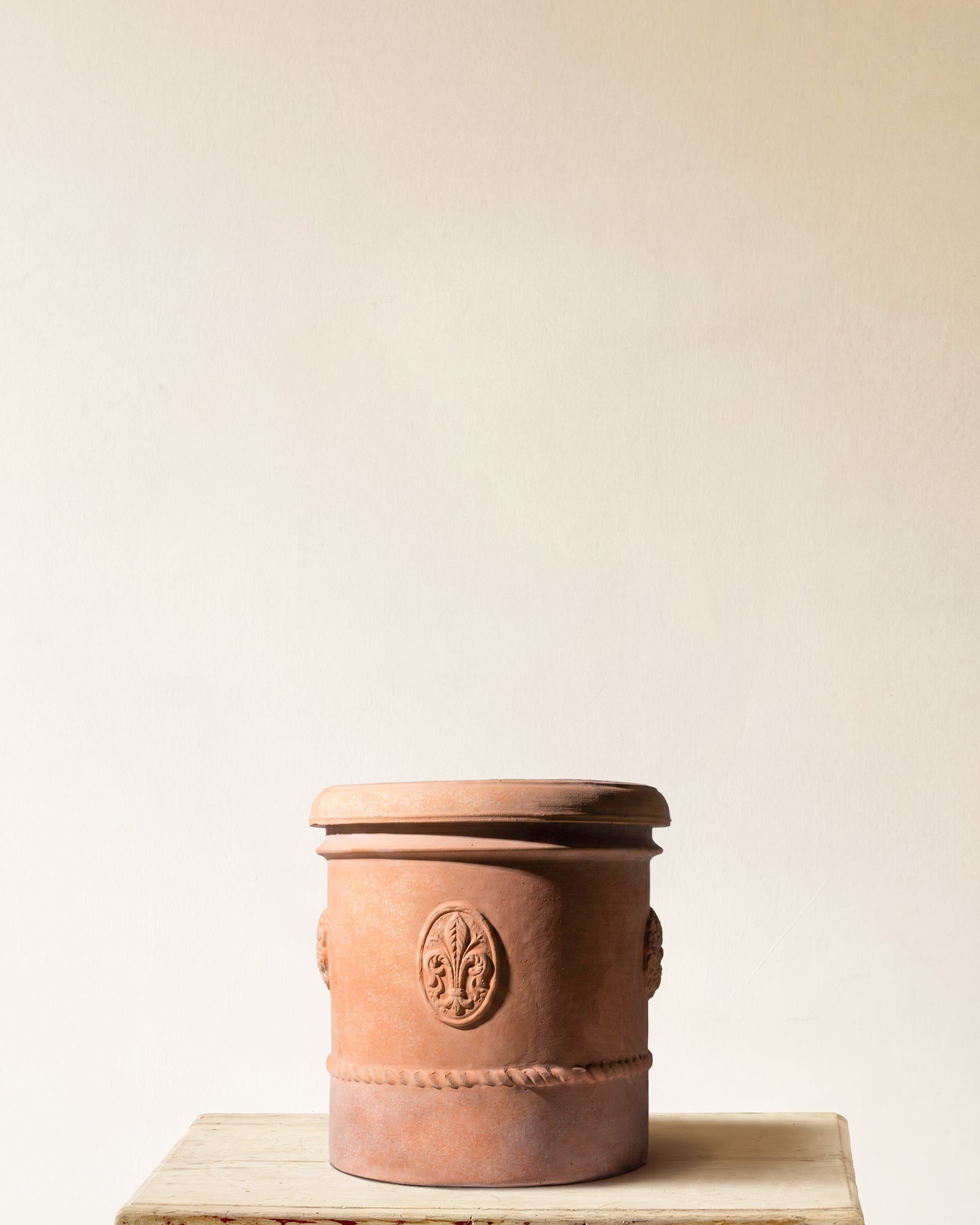 Italian terracotta planter with tall cylindrical form, projecting rim, raised medallion and rope band detail, made in Impruneta, 17" x 19", angled view